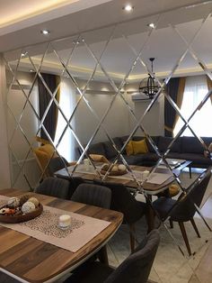 a dining room table with chairs and a mirror on the wall behind it that is reflecting an image of a living room