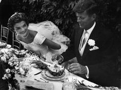 a bride and groom are cutting their wedding cake at the table in black and white