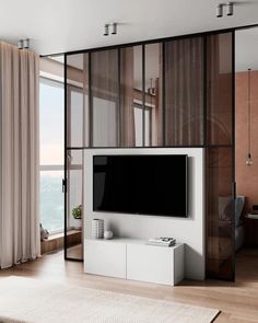 a flat screen tv sitting on top of a white cabinet in a living room next to a window