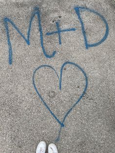 someone's feet are standing in front of the sidewalk that has graffiti on it