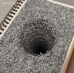 an open spiral notebook with black and white doodles on the cover, showing a hole in the middle