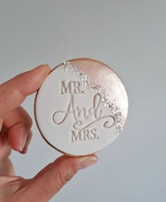 a person holding up a cookie with the words mr and mrs on it