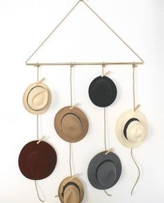 several hats hanging on a wall with strings