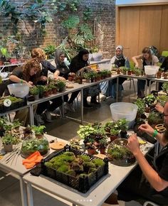 a group of people sitting around tables with plants