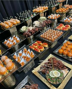 an assortment of food items displayed on trays at a party or function table with black backdrop