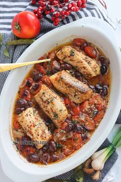 fish stew with tomatoes and olives in a white bowl on top of a table