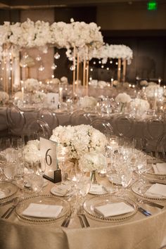 the table is set with white flowers and place settings