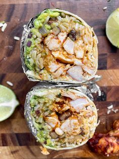 two burritos filled with meat and vegetables sitting on top of a wooden cutting board