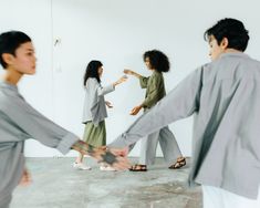 four people are dancing in an empty room with one person holding the other's hand