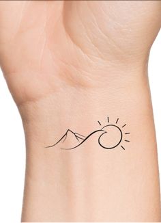 a small wrist tattoo with the sun and mountains in the background, on a woman's left arm