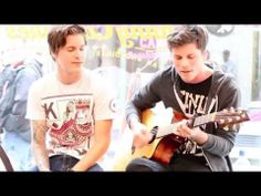 two young men sitting next to each other playing guitars