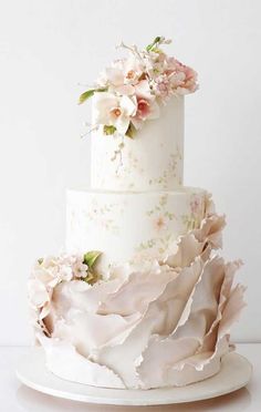 a three tiered wedding cake with flowers on top