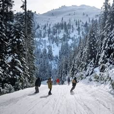 three people snowboarding down a snowy mountain road