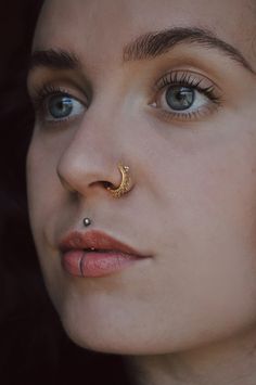 a close up of a woman with piercings on her nose and nose ring in front of her face