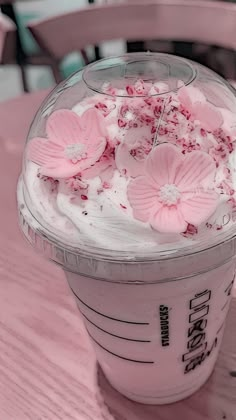 a pink drink with white frosting and flowers in it sitting on a wooden table