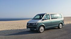 a van is parked on the beach by the water