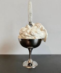 an ice cream sundae in a black bowl with a spoon sticking out of it