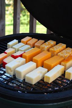 several different types of cheese are cooking on a bbq grill with the lid open