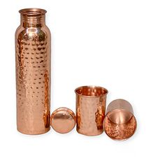 a copper colored vase and three cups