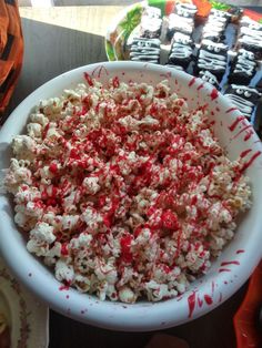 a white bowl filled with popcorn covered in red sprinkles on top of a table