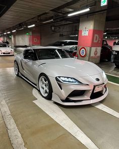 two cars parked in a parking garage next to each other on the floor and one is white