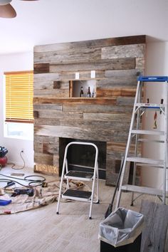 a living room that is being remodeled with wood paneling on the wall and a fire place