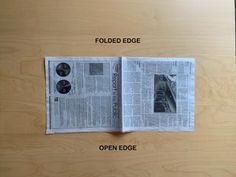 an open newspaper on top of a wooden table with the words folded edge and open edge