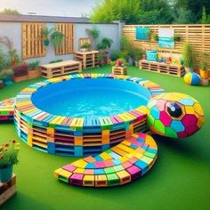 an outdoor pool made out of wooden pallets and painted with bright colors, sits in the middle of a backyard