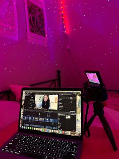 a laptop computer sitting on top of a table in front of a pink wall with stars