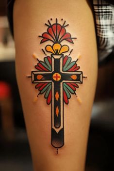 a woman's thigh with a cross tattoo design on it and an orange flower