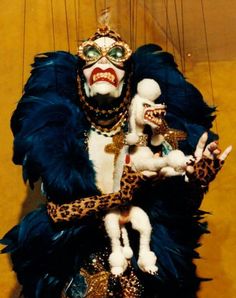 a man dressed in costume holding a doll with chains hanging from it's sides