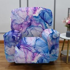 a chair covered in blue, purple and white fluid paint sitting on top of a hard wood floor