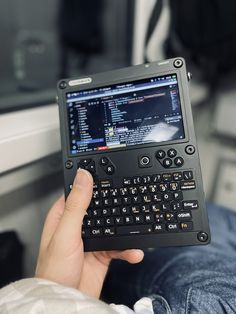 a person is holding up a small tablet with a keyboard on it's screen