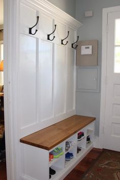 an entryway with white cabinets and wooden bench