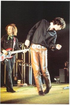 two young men are playing guitars on stage