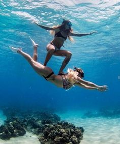 two women in bikinis are diving under the water