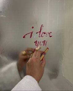 a person writing on a metal surface with pink ink and gold trimmings, while holding a pair of scissors in their left hand