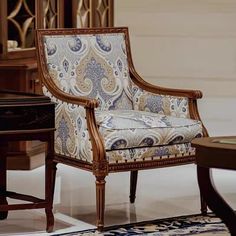 an ornate chair sits in front of a table with a piano and vase on it