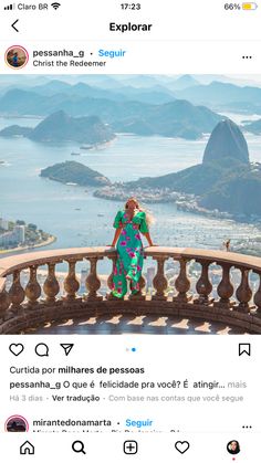 a woman standing on top of a balcony next to the ocean and mountains with her hands in her pockets