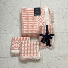 three pieces of orange and white patterned towels on the floor with a black ribbon tied around them