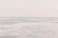 an ocean view with waves crashing on the shore and one person walking in the water