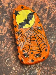 an orange painted rock with bats and spider webs on it