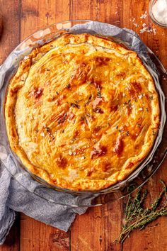 a pie sitting on top of a wooden table next to a glass bowl filled with food