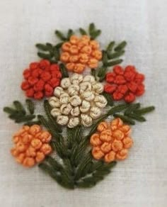 a close up of a flower on a white cloth with orange and red flowers in the center