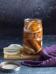 a jar filled with pickles and sliced onions on top of a wooden cutting board