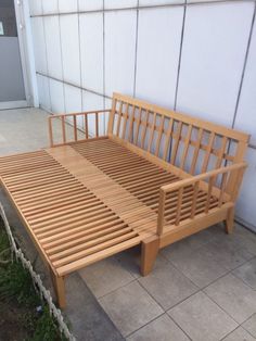 a wooden bench sitting on top of a cement floor next to a wall and grass