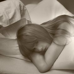 a woman laying in bed with her head on the pillow