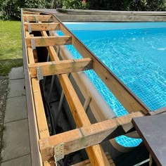 an above ground swimming pool being constructed with wooden rafts and blue tiles on the water