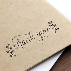 the word thank you written in cursive ink on a piece of brown paper