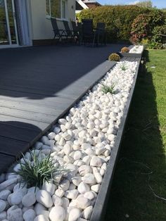 a garden with rocks and plants on the side of it, in front of a house